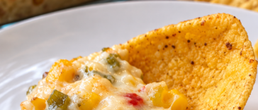 Creamy cheesy corn and green chile dip served warm with corn chips