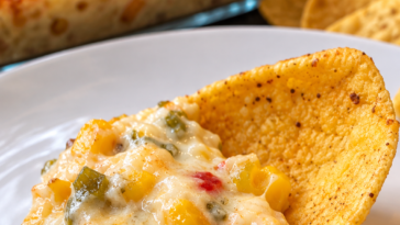 Creamy cheesy corn and green chile dip served warm with corn chips